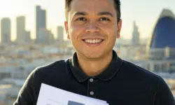 Hombre sonriente sosteniendo documentos impresos con un fondo de ciudad moderna.